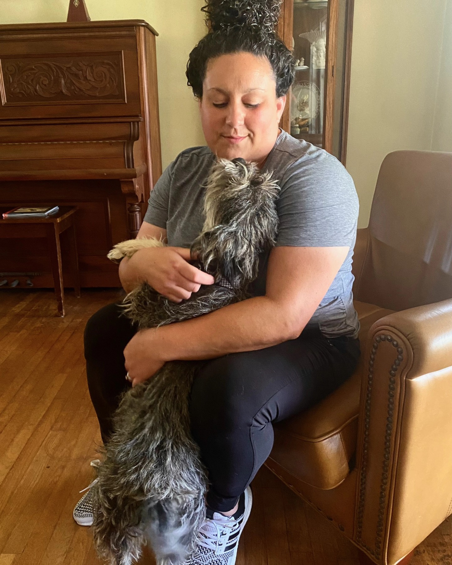 Alexandra Macias sitting with a scruffy gray dog on her lap